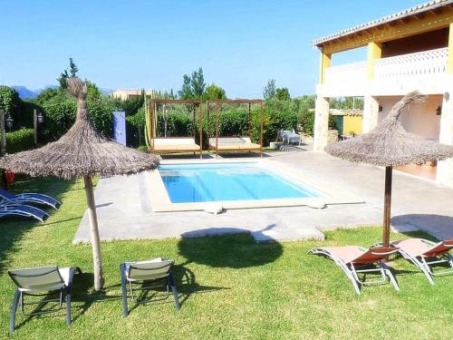 a yard with chairs and umbrellas and a swimming pool at Villa Son Fanals in Alcudia