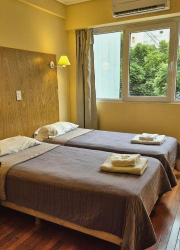 two beds in a room with a window at Hotel Juramento in Buenos Aires