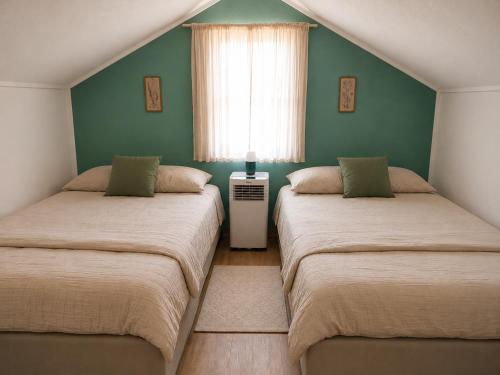two beds in a room with green walls and a window at Privatni smještaj Kurtalija in Jajce