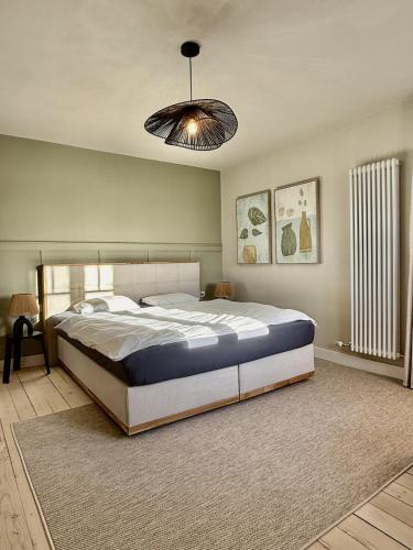 a bedroom with a large bed and a chandelier at Villa El Jardin Bodensee in Lochau