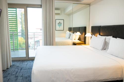 a hotel room with a large bed and a large window at Baileys Serviced Apartments in Perth
