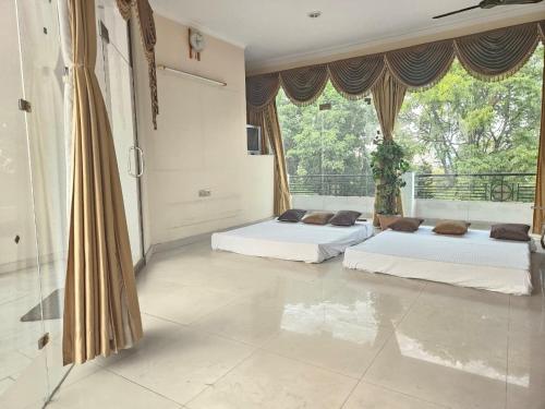 two beds in a room with a large window at The Green Villa in Ludhiana