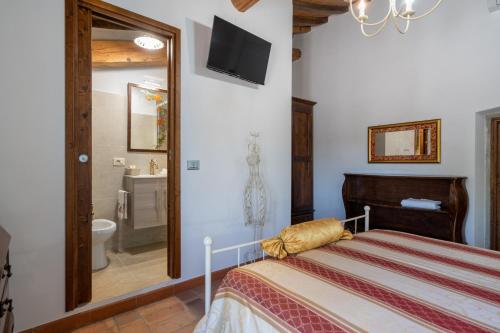 a bedroom with a bed and a tv on the wall at La Campana d'Oro Bibbiena in Bibbiena