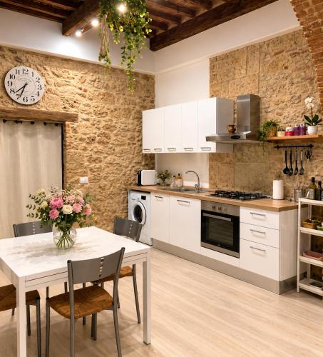 a kitchen with a table and a clock on the wall at La Casina del Corso in Massa Marittima