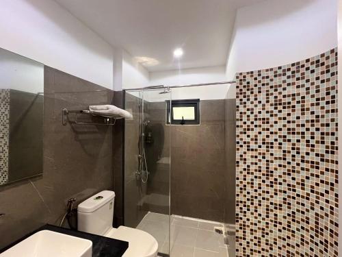 a bathroom with a toilet and a glass shower at Khách Sạn PG Boutique in Vung Tau