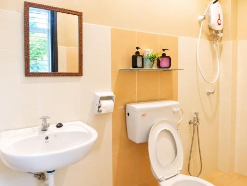 a bathroom with a sink and a toilet and a mirror at Family Retreat w Kid Pool, BBQ Games Sleeps 10pax Melaka in Kampong Beringin