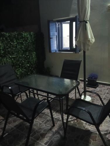 a glass table and chairs with an umbrella at Mary's home in Atsikí