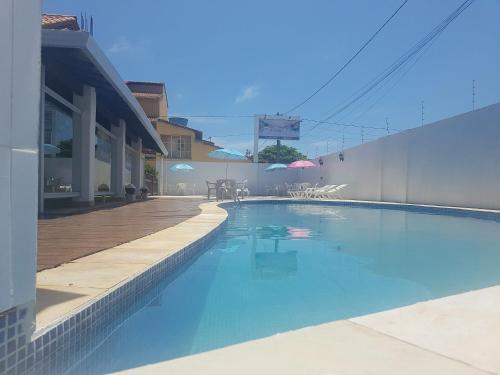 a swimming pool next to a building with a deck at Pousada Paradise in Alcobaça