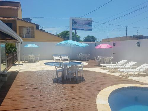 a patio with tables and chairs with umbrellas and a pool at Pousada Paradise in Alcobaça