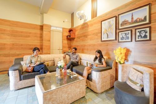 a group of people sitting on couches in a living room at Fabhotel Grant Heights - Nr Biju Patnaik International Airport in Bhubaneshwar