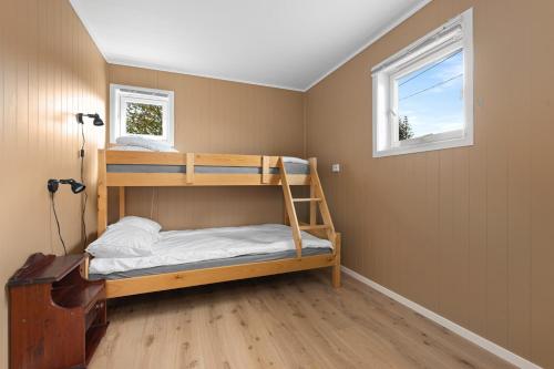 a bedroom with two bunk beds and a window at Beach cottage in Søgne in Kristiansand