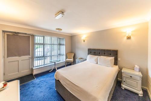 a bedroom with a large bed and a window at Littleover Lodge Hotel in Derby