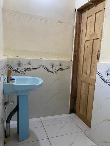 a bathroom with a blue sink next to a door at Kalash Echo Lodge in Chitral