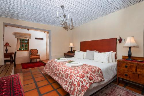 a bedroom with a bed and a table and a chair at Oue Werf Country House in Oudtshoorn