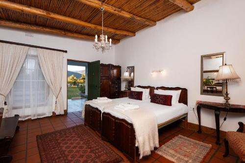 a bedroom with a large bed and a table at Oue Werf Country House in Oudtshoorn