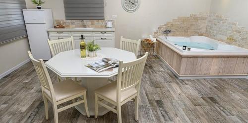a kitchen with a table and a tub and a table and chairs at בקתות לוטן דלתון - 4 בקתות עם ג'קוזי פרטי ו-2 בריכות משותפות in Shahar
