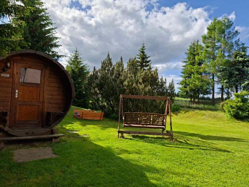 a wooden bench sitting in the grass next to a barrel at Forest House near Klínovec with 5 Independent Apartments in Kovářská