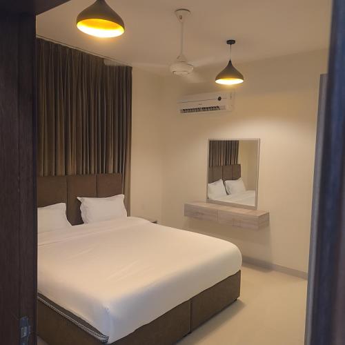 a bedroom with a large white bed and a mirror at Golden Seasons Rose in Salalah