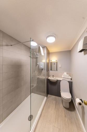a bathroom with a shower and a toilet and a sink at Littleover Lodge Hotel in Derby