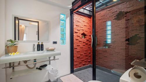 a bathroom with a sink and a shower with a brick wall at La Casa Bangtao Resort in Ban Thalat Choeng Thale