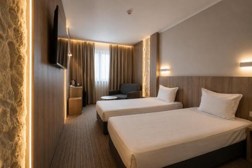 a hotel room with two beds and a chair at Aqua Hotel in Varna City