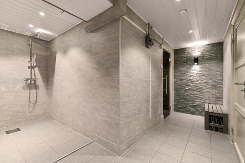 a bathroom with a walk in shower next to a stone wall at Gomobu Fjellstue in Ron
