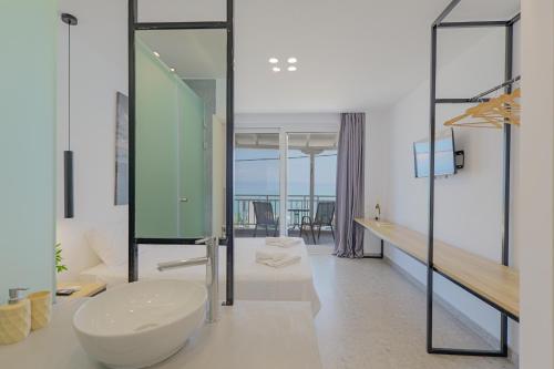 a bathroom with a sink and a glass wall at Salty Sea View Apartments in Polychrono