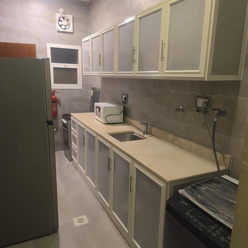 a kitchen with white cabinets and a sink at Golden Seasons Rose in Salalah