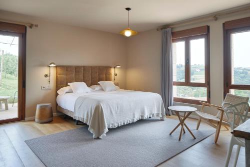 a bedroom with a large white bed and windows at Olivi1948 - Boutique Guest House in Usúrbil