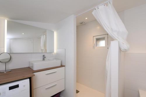 a white bathroom with a sink and a mirror at Maison Ty Bihan Sioul in Sarzeau