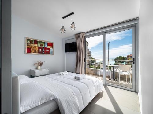 a white bedroom with a bed and a large window at Vourtaréa Guesthouse in Himare