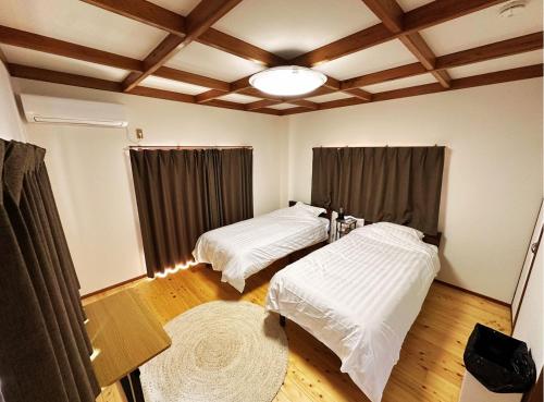 two beds in a room with wooden floors at MIYABI stay house in Tamana