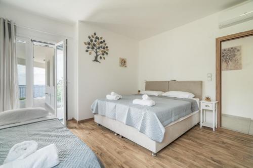 a white bedroom with two beds and a window at Perseus in Cape Sarakiniko in Argostoli