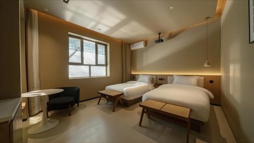 a bedroom with two beds and a table and a window at Qinxiang Pavilion Hotel in Dunhuang