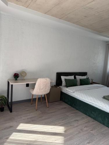 a bedroom with a bed and a desk and a chair at Апартамент САМИ 102 in Dobrich