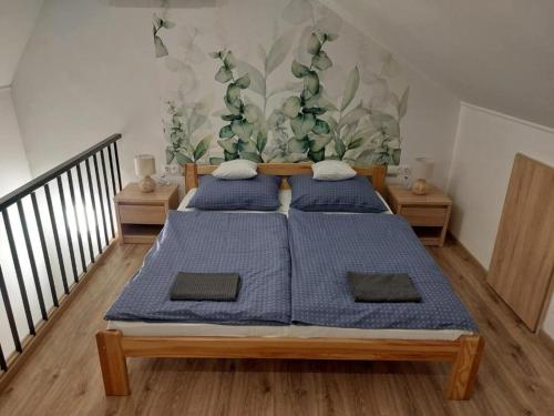 two beds in a room with a mural on the wall at Gilbert Apartman in Doboz