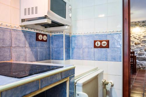 a kitchen with blue and white tiled walls at Baelo Claudia in Navalguijo