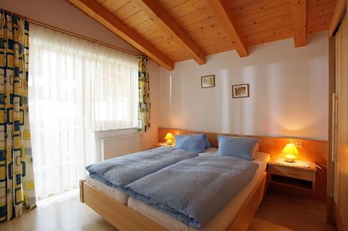 a bedroom with a bed with blue sheets and a window at Landhaus Nageler in Westendorf
