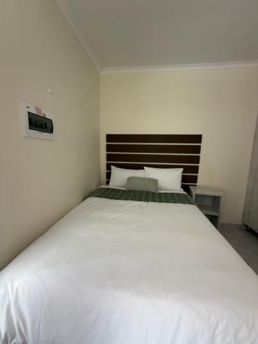 a bedroom with a large white bed with two pillows at Coastwave Guesthouse CBD in Walvis Bay