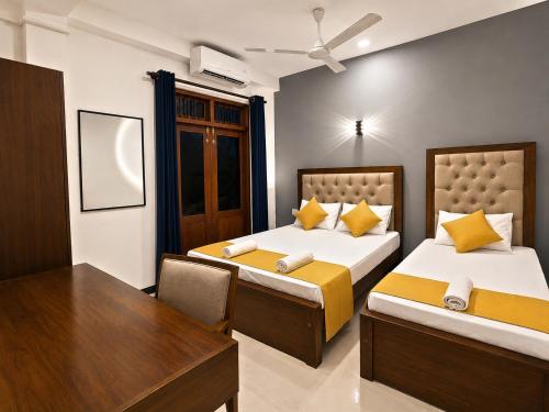 two beds in a room with a table and a desk at Hotel Dreamliners in Katunayaka