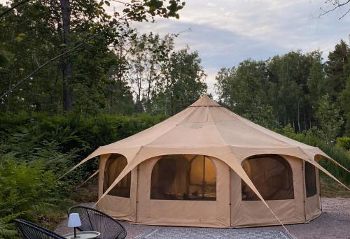 a canvas tent with a table and chairs in a field at Glamping Marsjön & Sauna in Rejböle