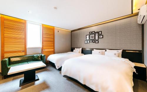 a bedroom with two beds and a green couch at Hotel Ssome Jeongkwan in Busan