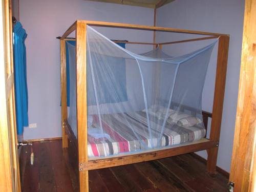ein Etagenbett aus Holz mit Baldachin in einem Zimmer in der Unterkunft Tampat do Aman in Kudat