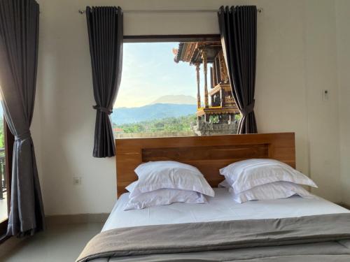 a bedroom with a bed with a large window at Qiana House in Manggis