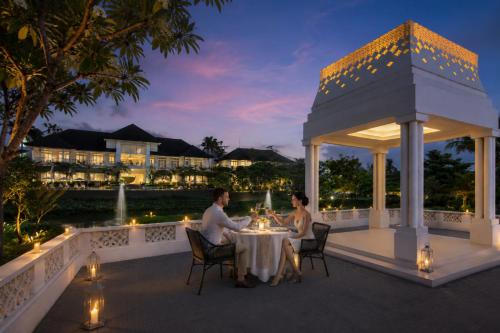 two people sitting at a table in a gazebo at night at Rumah Luwih Bali by IHG in Keramas