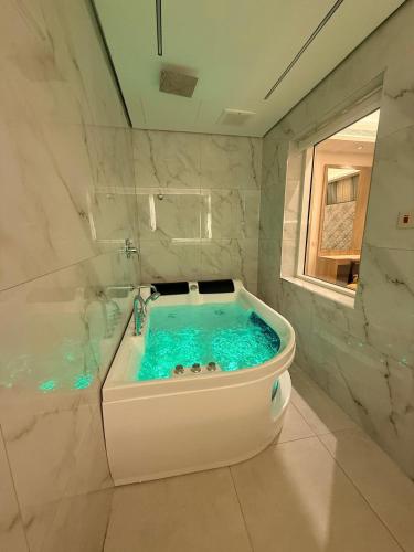 a bathroom with a tub with blue water in it at فندق أثير بارك in Jazan