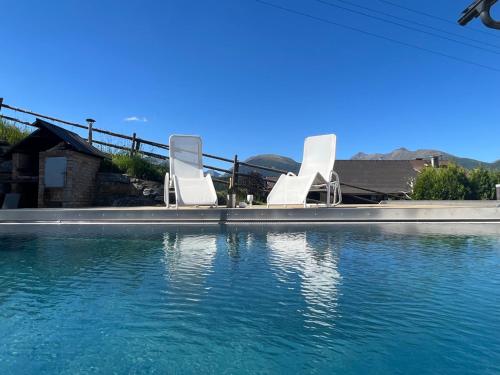 two white chairs sitting on the edge of a swimming pool at Ferienwelt Bogensperger in Mariapfarr