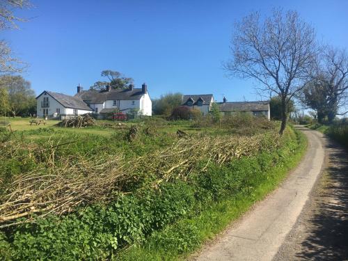 a dirt road next to a field with houses at Moorshead Farm Cottages in Llysworney
