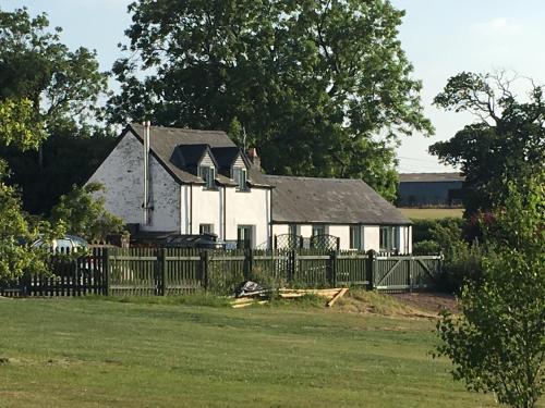 a white house with a fence in front of it at Moorshead Farm Cottages in Llysworney