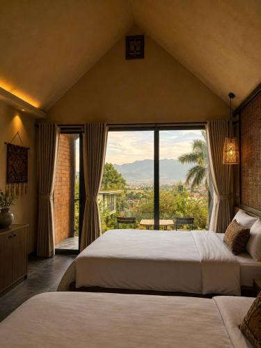 a bedroom with two beds and a large window at Chuồn Chuồn Resort Nghia Lo - Free Sauna & Onsen in Yên Bái